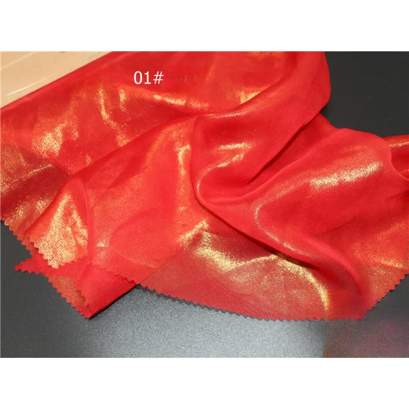 Un Tissu mousseline métallisé rouge brillant de Longan Craft France, présentant un reflet métallique doré, un bord rosé et étiqueté "01#", est présenté sur une surface plane.