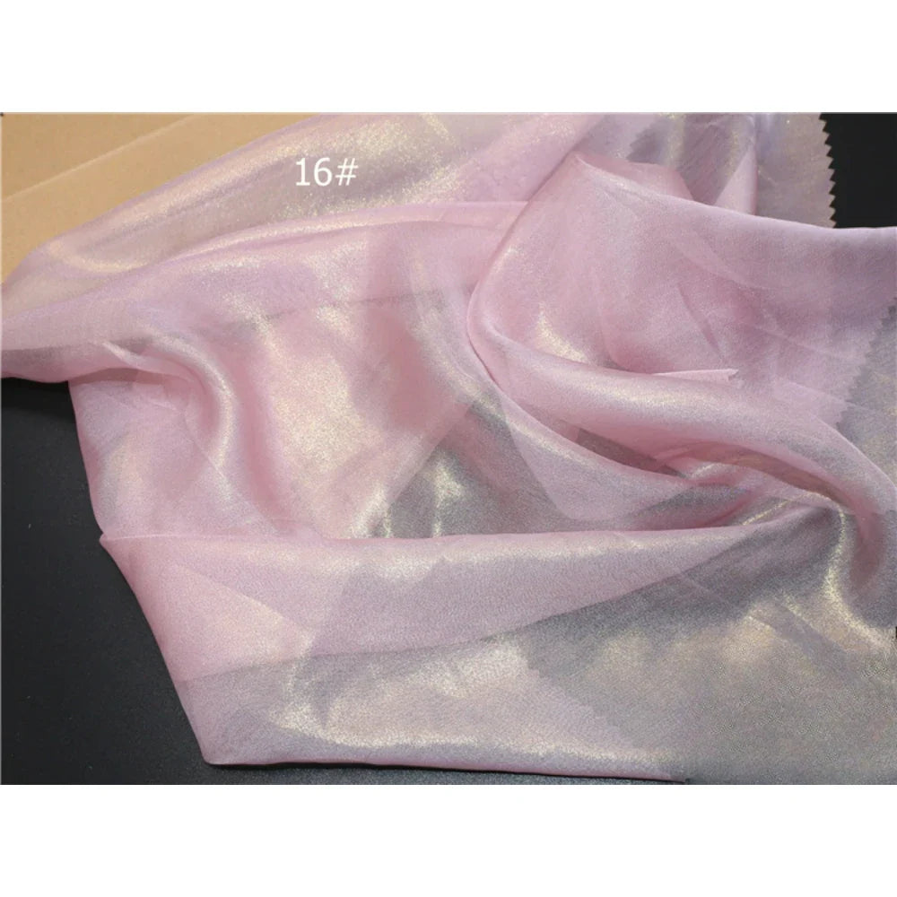 Un tissu mousseline brillant d'un rose irisé de Longan Craft France, étiqueté "16#", est étalé pour mettre en valeur sa texture délicate et chatoyante. Parfait comme tissu mousseline métallisé au mètre ou multicolore pour couture.