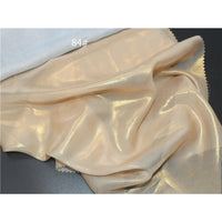 Un tissu mousseline beige clair métallisé au mètre par Longan Craft France, présentant une finition brillante et légèrement transparente, est présenté à côté d'un tissu blanc. Le numéro "84#" apparaît en texte blanc sur l'image.