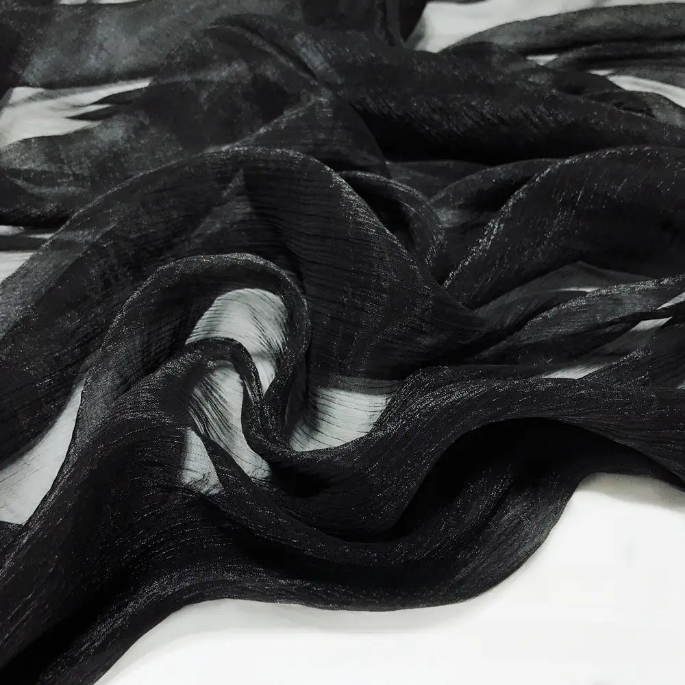 Gros plan sur le Tissu mousseline plissé brillant au mètre de Longan Craft France, une mousseline de polyester noire, transparente et légèrement froissée, superposée à du blanc, parfaite pour des projets élégants et légers.