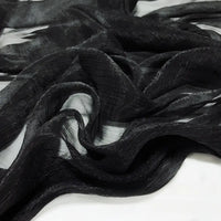 Gros plan sur le Tissu mousseline plissé brillant au mètre de Longan Craft France, une mousseline de polyester noire, transparente et légèrement froissée, superposée à du blanc, parfaite pour des projets élégants et légers.