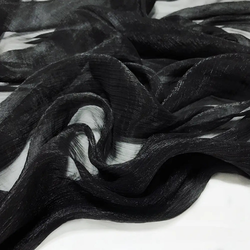 Gros plan sur le Tissu mousseline plissé brillant au mètre de Longan Craft France, une mousseline de polyester noire, transparente et légèrement froissée, superposée à du blanc, parfaite pour des projets élégants et légers.