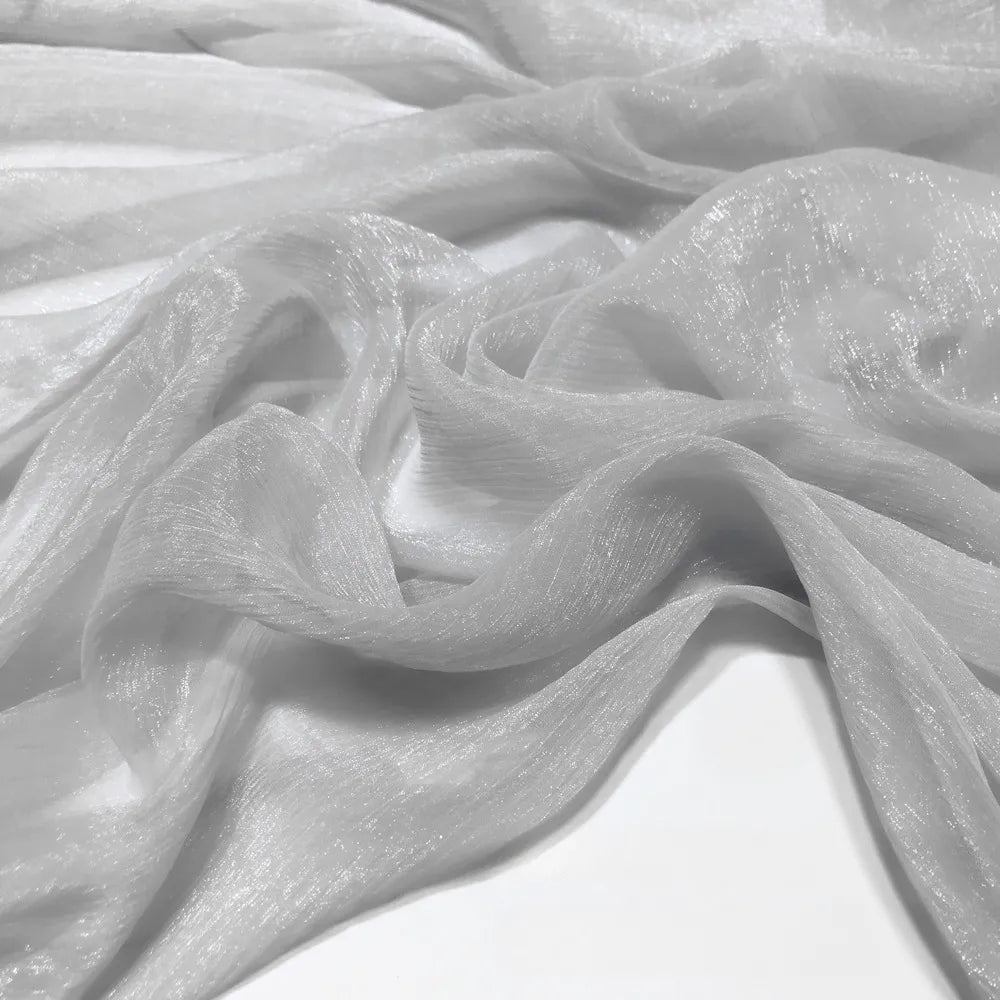 Gros plan sur le tissu mousseline plissé brillant au mètre de Longan Craft France - un tissu de polyester léger, brillant et froissé - posé librement sur une surface.
