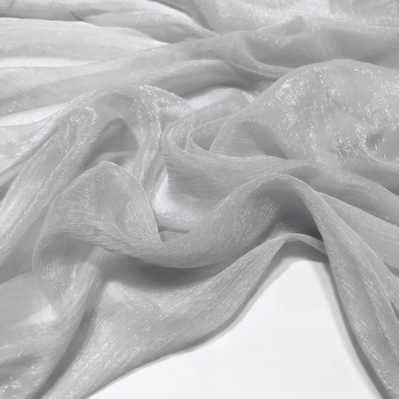 Gros plan sur le tissu mousseline plissé brillant au mètre de Longan Craft France - un tissu de polyester léger, brillant et froissé - posé librement sur une surface.