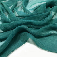 Gros plan sur la mousseline plissée brillant au mètre de Longan Craft France : un tissu léger et transparent en polyester de couleur vert sarcelle, avec une texture froissée et des plis doux et ondulés sur un fond blanc.