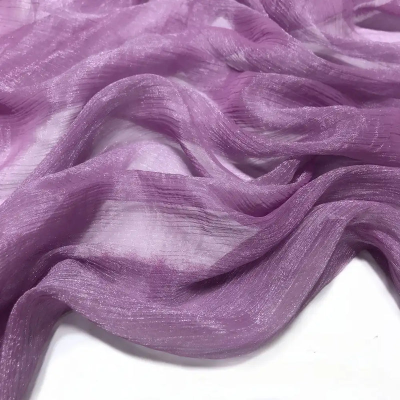 Gros plan sur le Tissu mousseline plissé brillant au mètre de Longan Craft France : un polyester violet léger, transparent et froissé avec une finition légèrement brillante, doucement drapé et froncé sur un fond blanc.