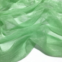 Gros plan sur le tissu mousseline plissé brillant semi-transparent vert clair de Longan Craft France, à la texture légèrement froissée et aux plis doux, disponible au mètre en polyester léger.