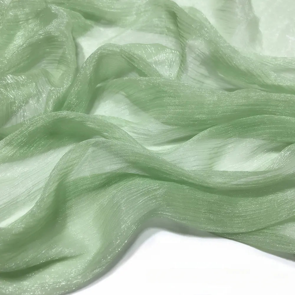 Gros plan sur le tissu mousseline plissé brillant au mètre vert clair de Longan Craft France, un polyester texturé transparent et légèrement brillant drapé sur un fond blanc.