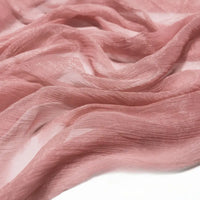 Un gros plan du tissu mousseline plissé brillant au mètre de Longan Craft France montre un tissu de polyester rose clair, transparent et légèrement brillant, aux plis fluides - une matière légère et plissée parfaite pour des créations élégantes.