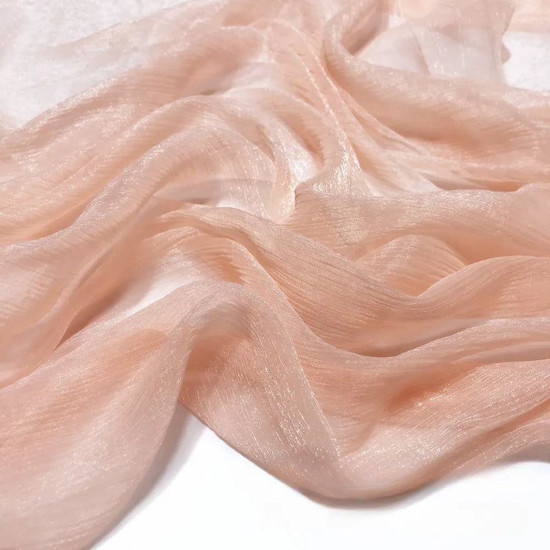 Gros plan sur le tissu polyester plissé mousseline multicolore de Longan Craft France, qui présente une texture brillante et légèrement froissée avec des plis doux et fluides sur un fond blanc.