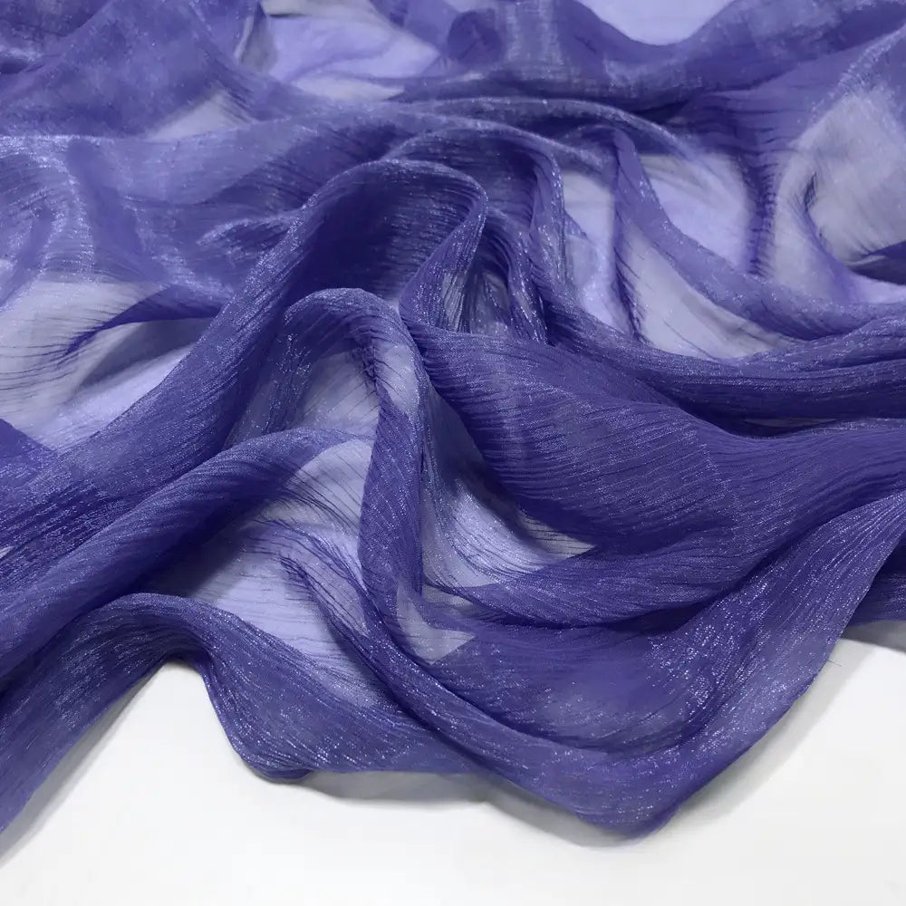 Gros plan sur le Tissu mousseline plissé brillant au mètre de Longan Craft France, un tissu léger, brillant et plissé en polyester multicolore, présenté en plis souples et fluides sur une surface blanche.