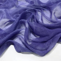 Gros plan sur le Tissu mousseline plissé brillant au mètre de Longan Craft France, un tissu léger, brillant et plissé en polyester multicolore, présenté en plis souples et fluides sur une surface blanche.