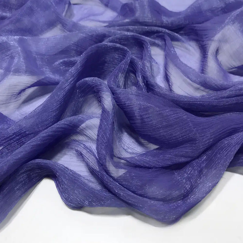 Gros plan sur le Tissu mousseline plissé brillant au mètre de Longan Craft France, un tissu léger, brillant et plissé en polyester multicolore, présenté en plis souples et fluides sur une surface blanche.