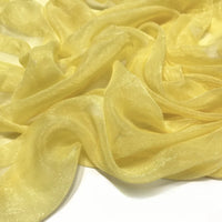 Un gros plan du Tissu mousseline plissé brillant au mètre de Longan Craft France montre un polyester transparent, léger et froissé avec des plis doux et une texture légèrement brillante et translucide.