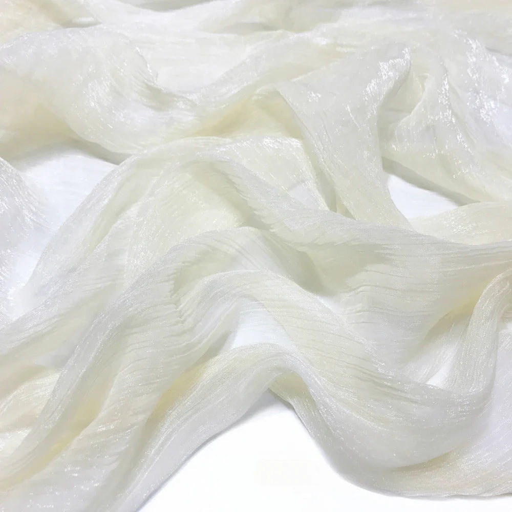 Gros plan sur le Tissu mousseline plissé brillant au mètre de Longan Craft France, une mousseline de polyester transparente et légère, à la texture brillante et froissée et aux teintes multicolores, élégamment drapée en plis souples.
