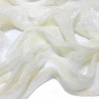 Gros plan sur le Tissu mousseline plissé brillant au mètre de Longan Craft France, une mousseline de polyester transparente et légère, à la texture brillante et froissée et aux teintes multicolores, élégamment drapée en plis souples.