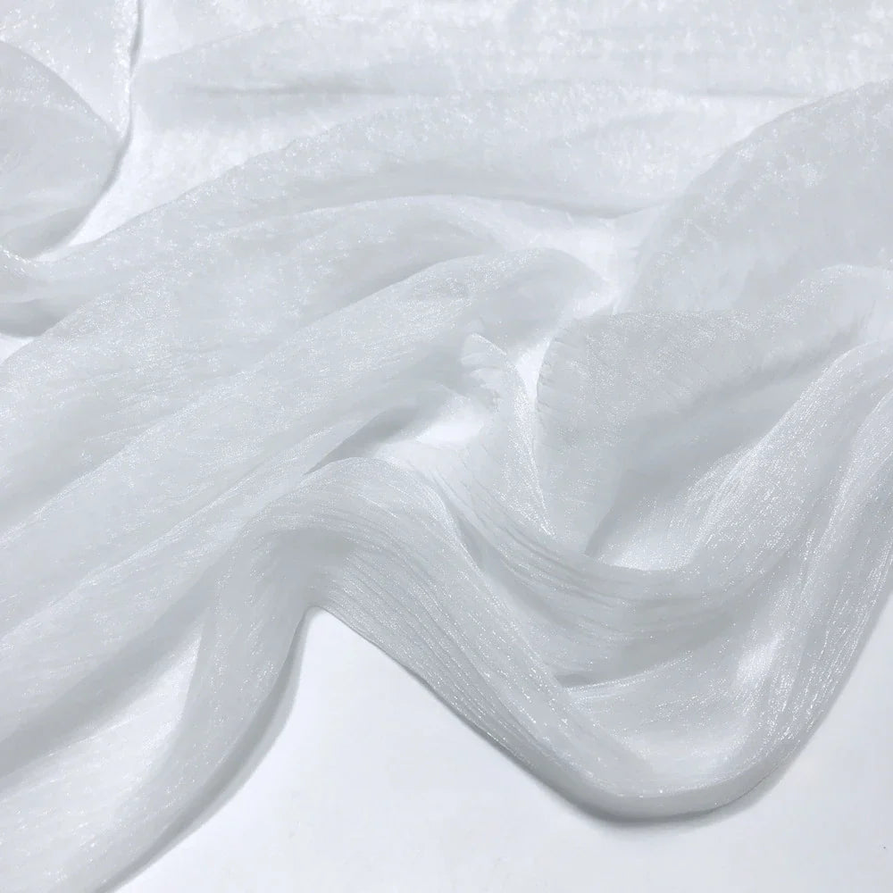 Gros plan sur le tissu polyester plissé mousseline multicolore de Longan Craft France, à la texture diaphane et semi-transparente et aux légers plis, drapé librement sur une surface plane.