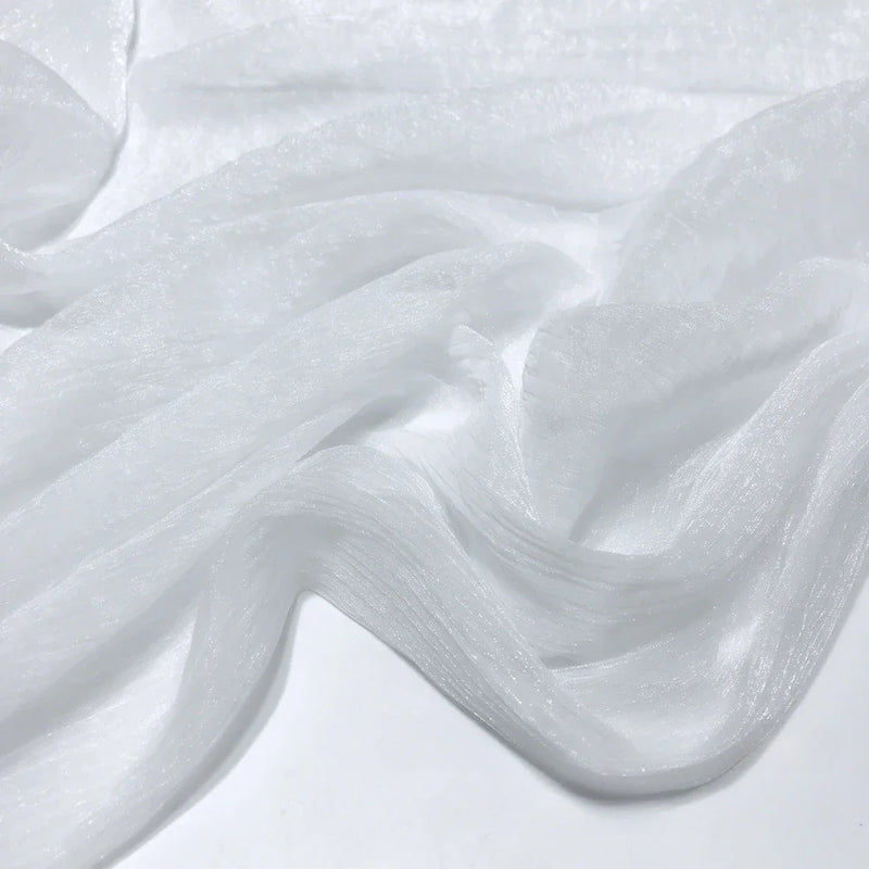 Gros plan sur le tissu polyester plissé mousseline multicolore de Longan Craft France, à la texture diaphane et semi-transparente et aux légers plis, drapé librement sur une surface plane.