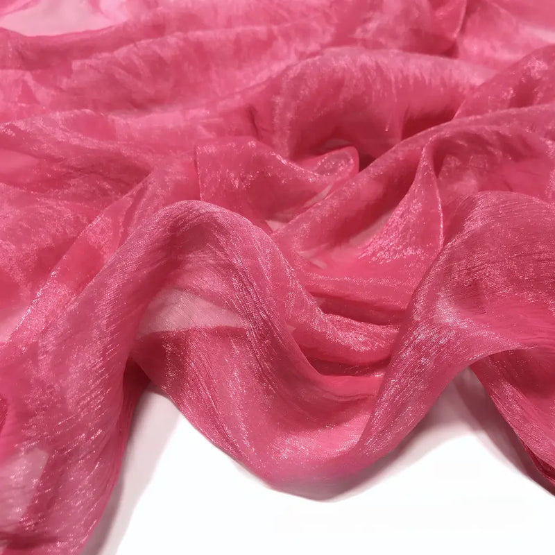 Gros plan sur le Tissu mousseline plissé brillant au mètre de Longan Craft France, un tissu léger et brillant en polyester plissé, présenté en plis souples sur une surface blanche.