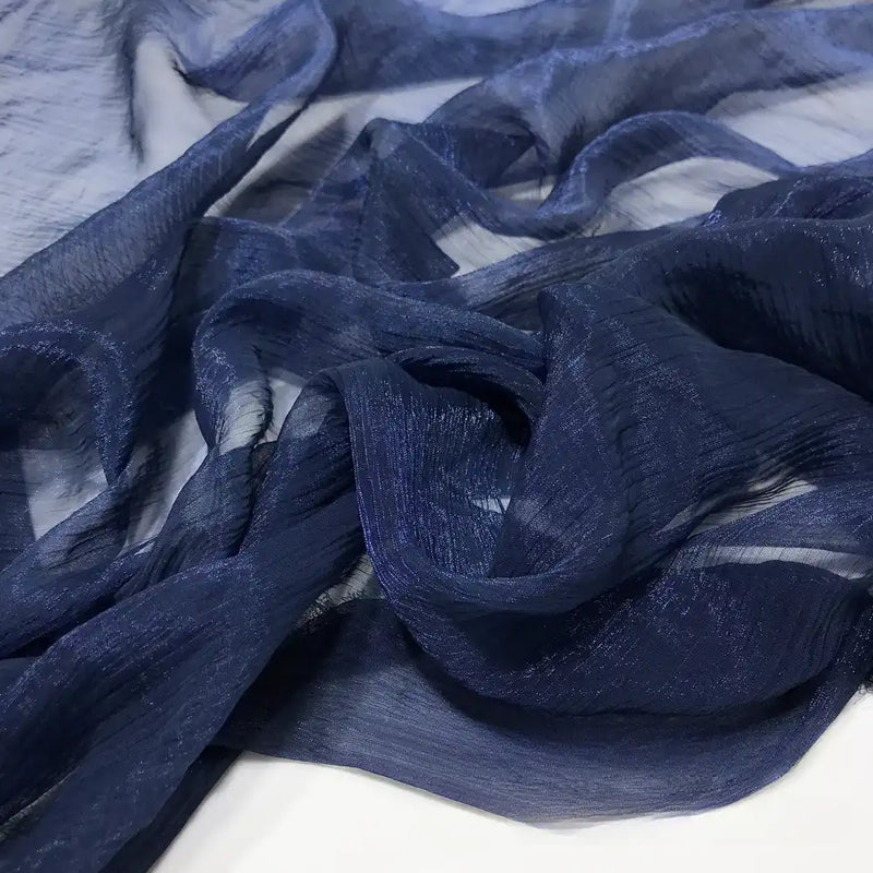 Gros plan sur du Tissu mousseline plissé brillant au mètre, bleu marine, semi-transparent et froissé, de Longan Craft France, montrant sa surface légèrement texturée sur un fond clair.