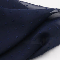 Un gros plan de Mousseline à plumetis au mètre de Longan Craft France révèle un tissu jacquard léger et diaphane dont la surface douce et légèrement transparente est parsemée de points multicolores délicatement en relief.