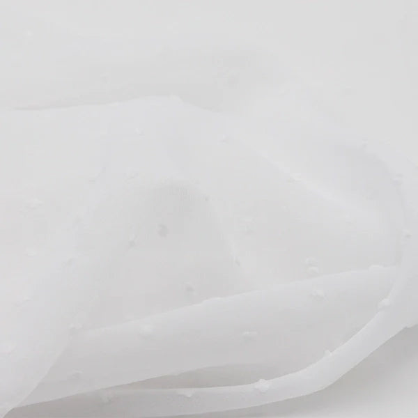 Un gros plan sur la Mousseline à plumetis au mètre de Longan Craft France montre son tissu jacquard léger et semi-transparent à la texture pointillée multicolore, doucement drapé pour mettre en valeur la délicatesse de la matière.