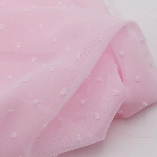 Gros plan sur la Mousseline à plumetis au mètre de Longan Craft France : tissu mousseline jacquard rose clair avec des points multicolores en relief, léger, doux et légèrement transparent.