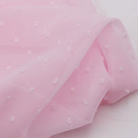 Gros plan sur la Mousseline à plumetis au mètre de Longan Craft France : tissu mousseline jacquard rose clair avec des points multicolores en relief, léger, doux et légèrement transparent.