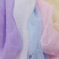Gros plan sur Mousseline à plumetis au mètre de Longan Craft France - tissus mousseline jacquard doux dans les tons pastel de lavande, blanc, bleu, rose et jaune avec une texture de points en relief, qui se superposent délicatement.