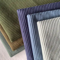 Une photo en gros plan montre des morceaux superposés de Longan Craft France Tissu côtelé polyester 4,5 côtes au mètre en vert, marron, bleu, gris clair et blanc cassé - chacun avec de larges côtes - idéal pour les pantalons ou la décoration intérieure.