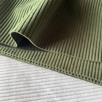 Gros plan sur le Tissu côtelé polyester 4,5 côtes au mètre de Longan Craft France en velours vert uni à côtes larges, drapé pour montrer les coutures nettes - idéal pour les pantalons ou la décoration intérieure.