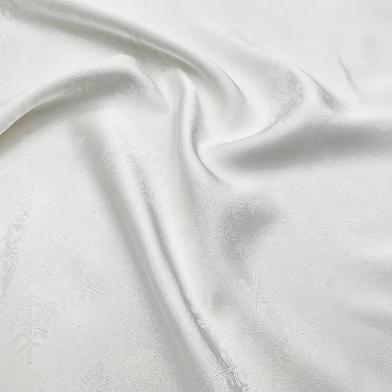 Le tissu satin jacquard motif flocon au mètre de Longan Craft France est un jacquard polyester blanc et soyeux, au lustre doux et aux subtils motifs de flocons de neige, parfait pour les robes. Le tissu lisse se drape magnifiquement et reflète la lumière en douceur.