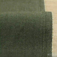 Gros plan sur un denim extensible Tissu vert foncé 9,5 oz de Longan Craft France, montrant sa fine trame diagonale et son bord légèrement effiloché, posé sur une surface en bois clair-idéal denim coton-polyester coloré pour jeans.