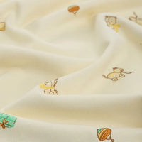 Gros plan sur le Jersey coton imprimé à motifs animaliers et botaniques au mètre de Longan Craft France, un tissu en jersey de coton de couleur crème avec des illustrations ludiques de chats et de fils dans des tons chauds, des plis souples et une texture lisse semblable à celle d'un sweat-shirt.