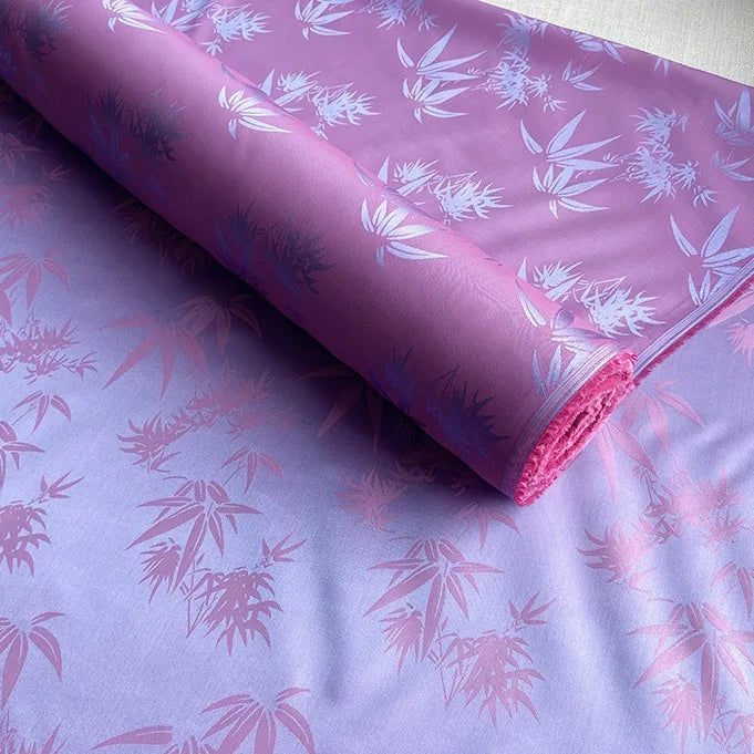 Un rouleau de tissu soie de mûrier et bambou imprimé jacquard au mètre de Longan Craft France, un tissu de doublure multicolore en soie et rayonne, est partiellement déroulé sur une surface plane.