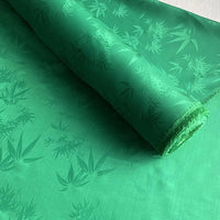 Une feuille partiellement déroulée du Tissu soie de mûrier et bambou imprimé jacquard au mètre de Longan Craft France, un tissu de doublure doux et confortable en soie et rayonne multicolore avec un élégant motif de feuilles de bambou.
