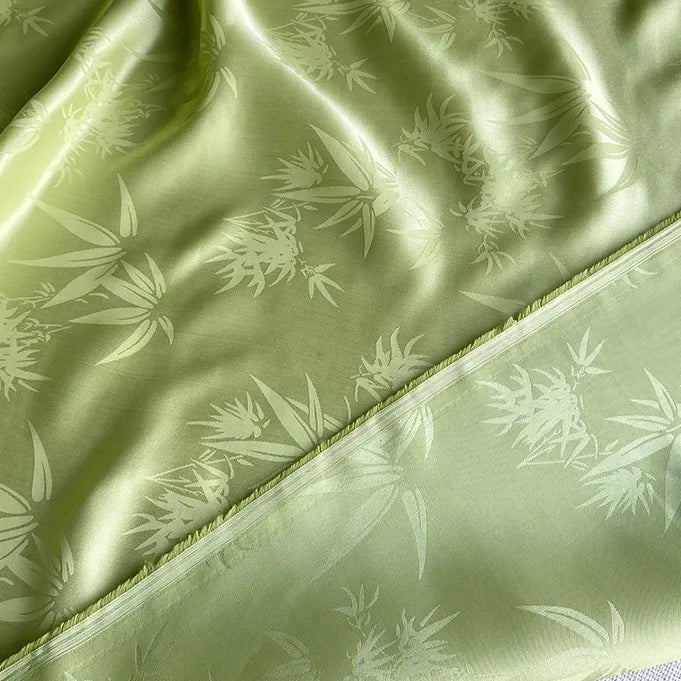 Gros plan sur le tissu soie de mûrier et bambou imprimé jacquard de Longan Craft France : tissu de doublure en soie-rayon vert clair au lustre subtil, au délicat motif de feuille de bambou et aux bords finis et non finis.