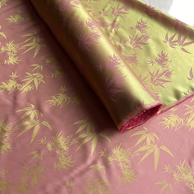 Gros plan sur le Tissu soie de mûrier et bambou imprimé jacquard au mètre de Longan Craft France, un tissu de doublure multicolore en soie et rayonne, montrant son motif brillant de feuille de bambou et ses deux faces avant et arrière.