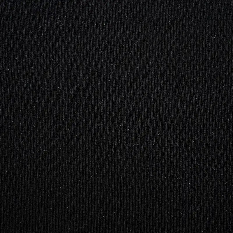 Un gros plan du Jersey bambou uni avec élasthanne de Longan Craft France montre sa surface noire subtilement texturée avec de fines fibres blanches. Ce textile doux est parfait pour des vêtements d'intérieur confortables.