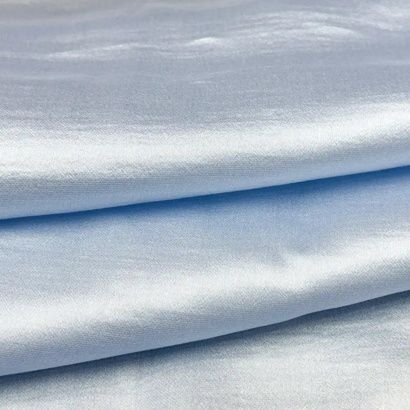 Des couches pliées de tissu en soie charmeuse de mûrier de Longan Craft France, un mélange de satin multicolore doux et fluide à la finition lisse et brillante, idéal pour les robes élégantes.