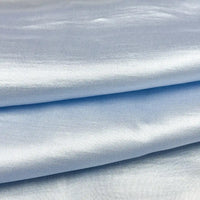 Des couches pliées de tissu en soie charmeuse de mûrier de Longan Craft France, un mélange de satin multicolore doux et fluide à la finition lisse et brillante, idéal pour les robes élégantes.