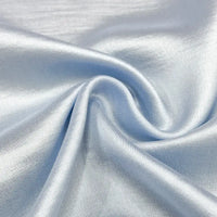 Gros plan sur le Tissu en soie charmeuse de mûrier au mètre de Longan Craft France, un tissu bleu clair, doux et fluide, composé d'un mélange de rayonne et de polyester, avec une finition lisse et brillante et des plis doux, idéal pour les robes élégantes.
