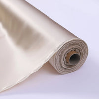 Gros plan sur le Tissu de soie charmeuse au mètre de Longan Craft France, déroulé sur une surface blanche, montrant sa texture lisse et brillante de soie de mûrier, idéale pour les robes de mariée luxueuses.