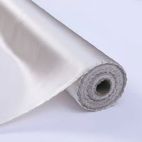Gros plan sur le Tissu de soie charmeuse au mètre de Longan Craft France, un tissu de soie de mûrier lisse et brillant, blanc ou ivoire, partiellement déroulé et présenté sur un fond clair uni - parfait pour les robes de mariée luxueuses.