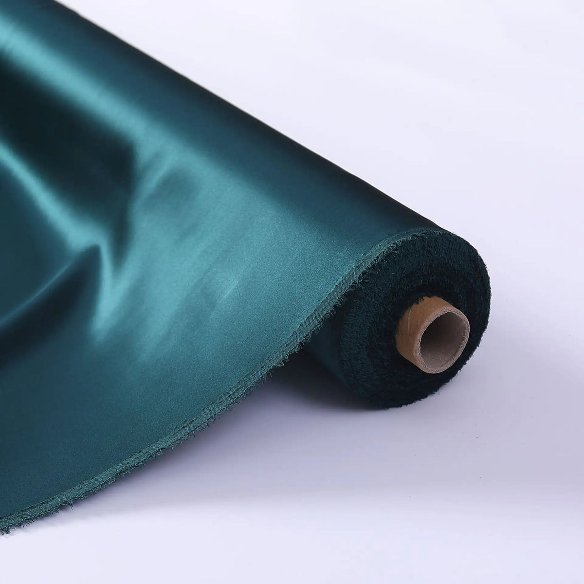 Un rouleau de tissu de soie charmeuse au mètre de Longan Craft France est présenté sur une surface blanche, mettant en valeur sa soie de mûrier lustrée et lisse - idéale pour les robes de mariée luxueuses - avec le recto et le verso visibles.