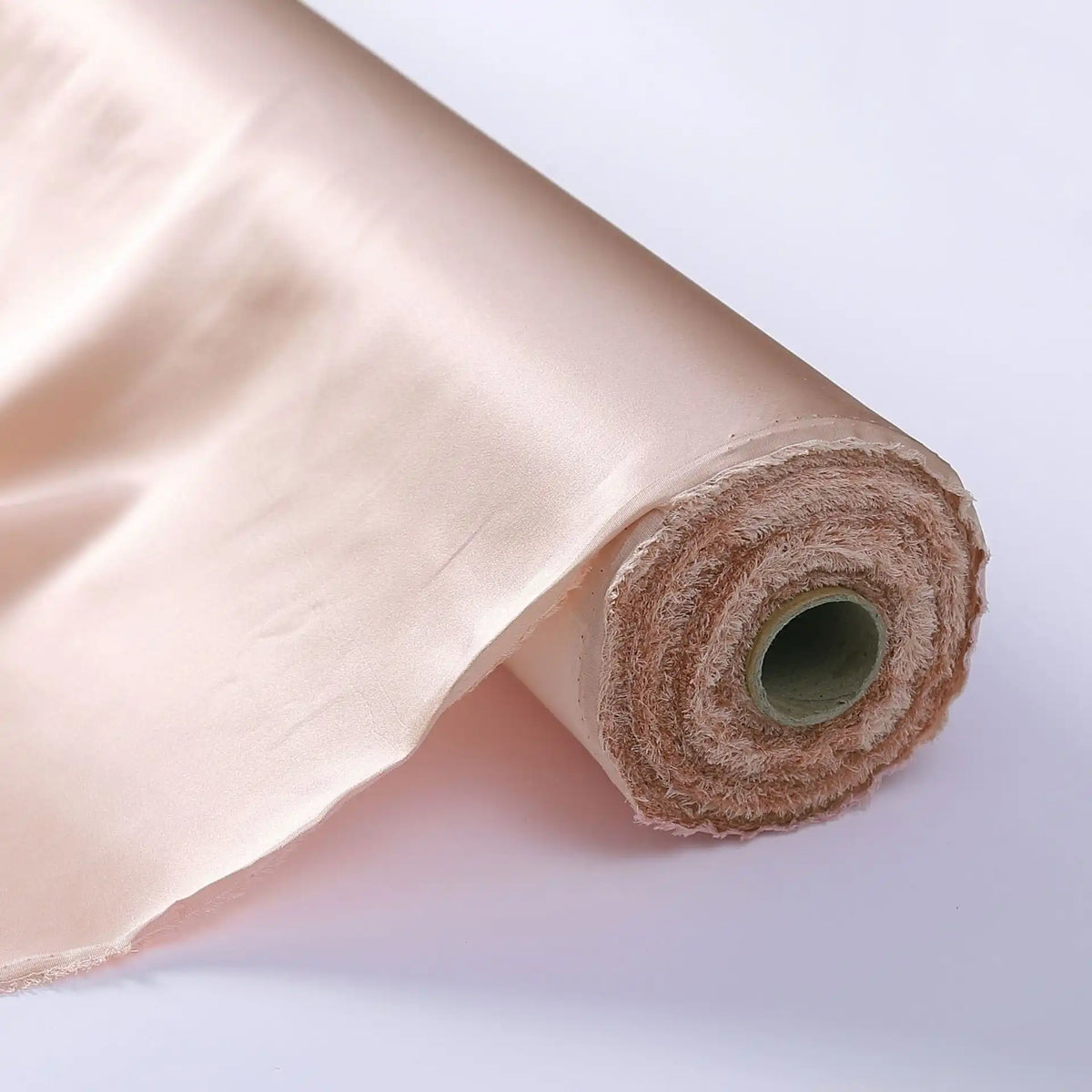 Un rouleau de Tissu de soie charmeuse au mètre de Longan Craft France est partiellement déroulé, montrant sa soie de mûrier lisse et brillante, parfaite pour les robes de mariée luxueuses, élégamment enroulée autour d'un tube en carton.