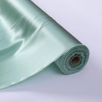Un rouleau de Tissu de soie charmeuse au mètre de Longan Craft France est partiellement déroulé sur une surface blanche, mettant en valeur sa soie de mûrier lisse et brillante, parfaite pour les robes de mariée luxueuses.
