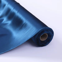 Un rouleau de Tissu de soie charmeuse au mètre de Longan Craft France, une soie Mulberry d'un bleu lustré parfaite pour les robes de mariée, est partiellement déroulé sur une surface blanche, montrant sa texture lisse et réfléchissante et son cœur en carton brun.