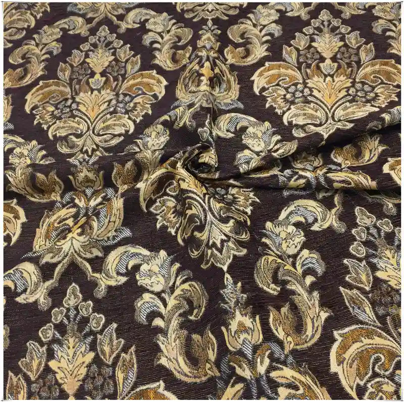 Gros plan sur le tissu damassé jacquard au mètre de Longan Craft France, montrant des motifs floraux or et beige détaillés sur un fond marron foncé, avec des plis élégants - idéal pour l'ameublement et la décoration d'intérieur.