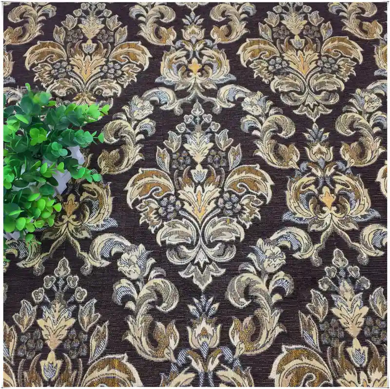 Tissu damassé jacquard au mètre de Longan Craft France (Tissu damassé jacquard au mètre), luxueux tissu damassé chenillé à motifs floraux, présenté avec des motifs beiges, or et crème. Une petite plante verte feuillue apparaît sur la gauche.